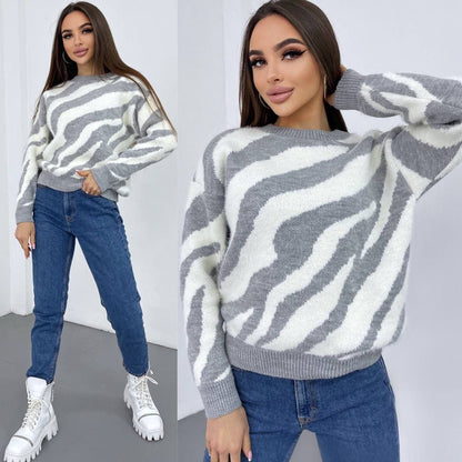 Woman wearing a gray and white zebra pattern sweater with blue jeans and white sneakers.