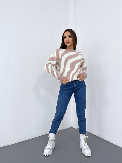 Woman wearing a striped sweater, blue jeans, and white sneakers against a white background