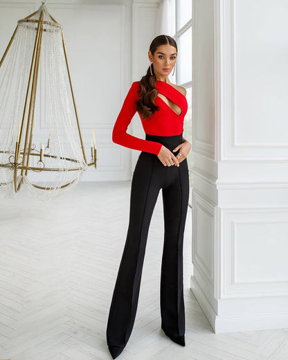 Woman in a red top and black pants standing in a stylish room with decorative elements.