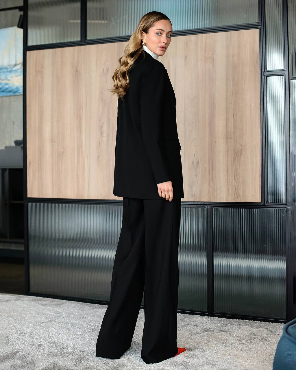 Woman in a black suit standing in an office setting