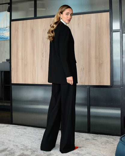 Woman in a black suit standing in an office setting
