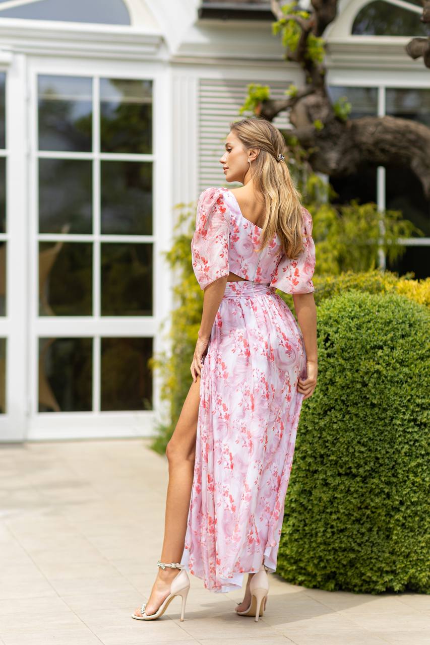 Woman in a pink floral dress standing in a garden setting