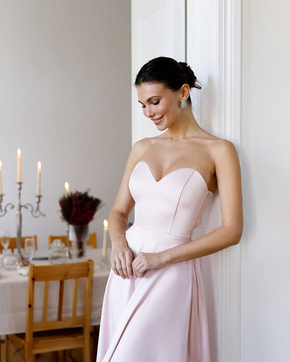 Woman in a strapless pink dress standing in a dining room.