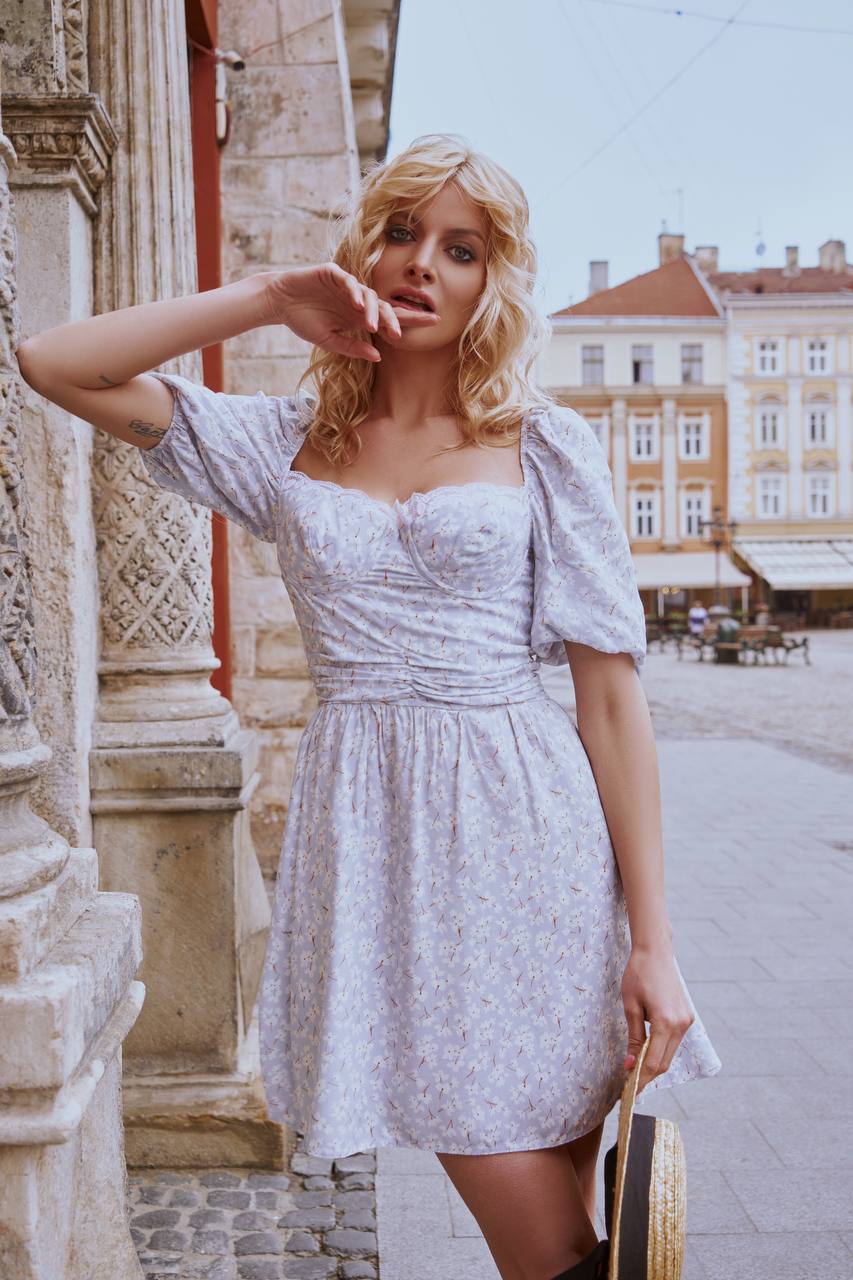 Woman in a light blue dress standing outdoors with historical architecture in the background