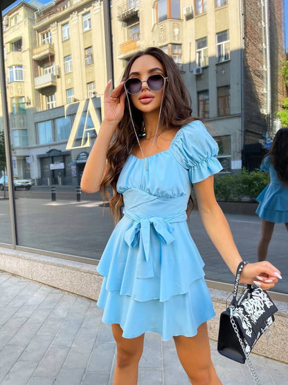 Woman in a light blue dress walking on a city street.