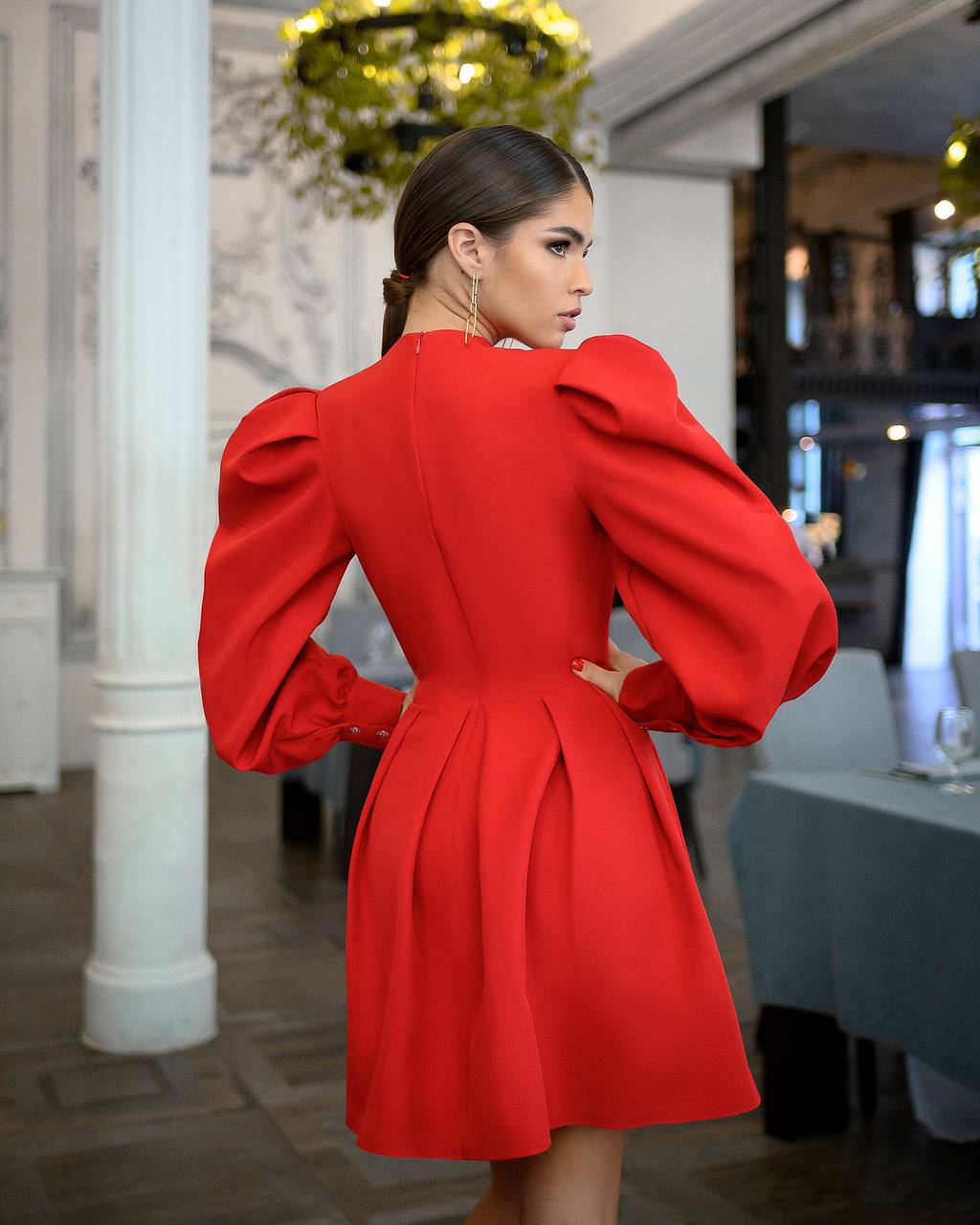 Woman wearing a red dress with puffed sleeves in an indoor setting