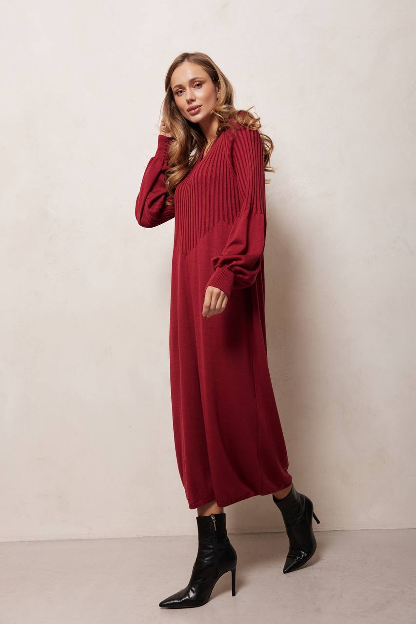 Woman wearing a red dress with long sleeves against a plain background