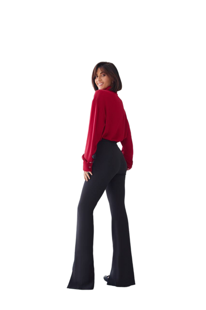 Person wearing a red top and black flared pants on a white background