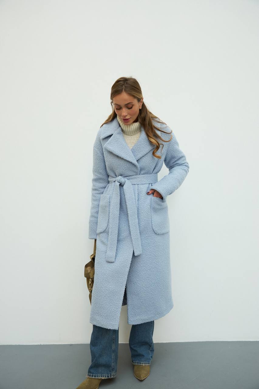 Woman wearing a light blue coat against a white background