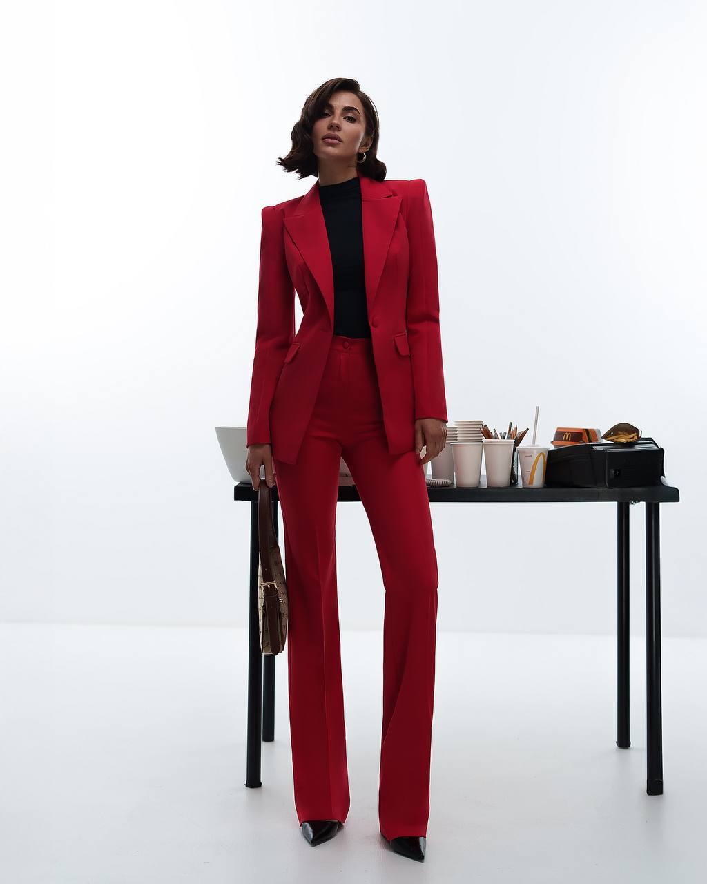 Person wearing a red suit standing in front of a table with items on it.