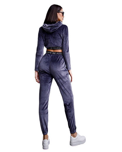 Woman wearing a gray velour tracksuit with white sneakers on a white background