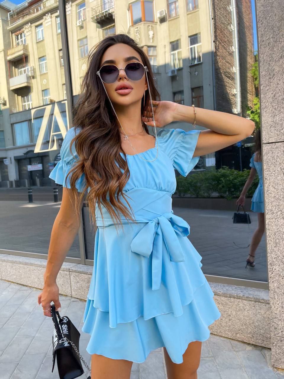 Woman in a light blue dress standing on a city street