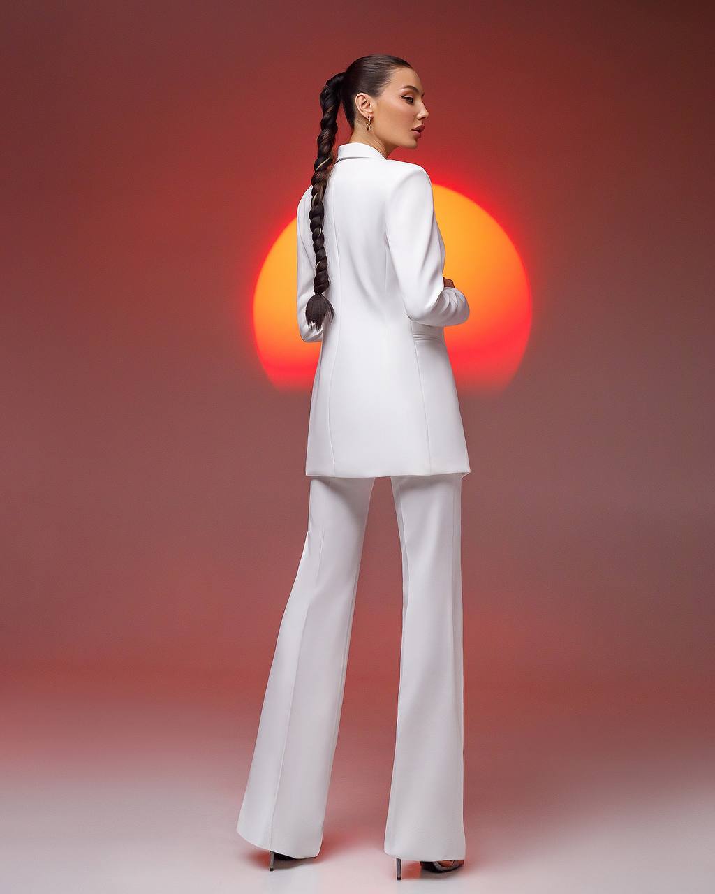 Woman in a white suit with a sunburst effect in the background