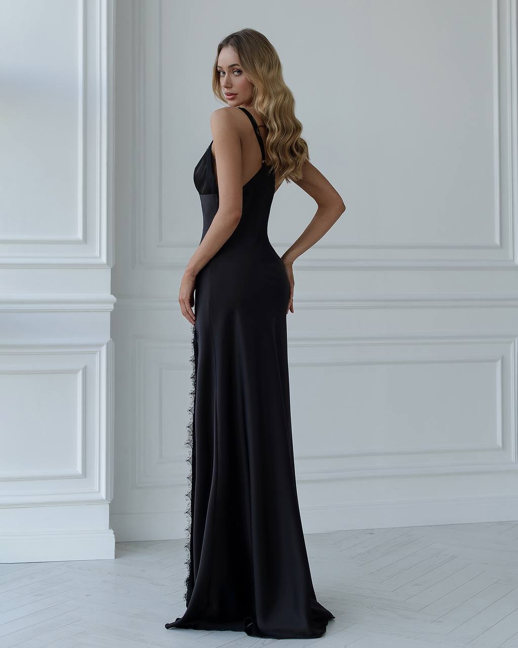 Woman wearing a black evening gown with a white wall background