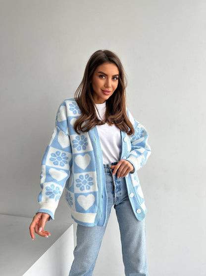 Woman wearing a light blue cardigan with heart patterns on a plain background