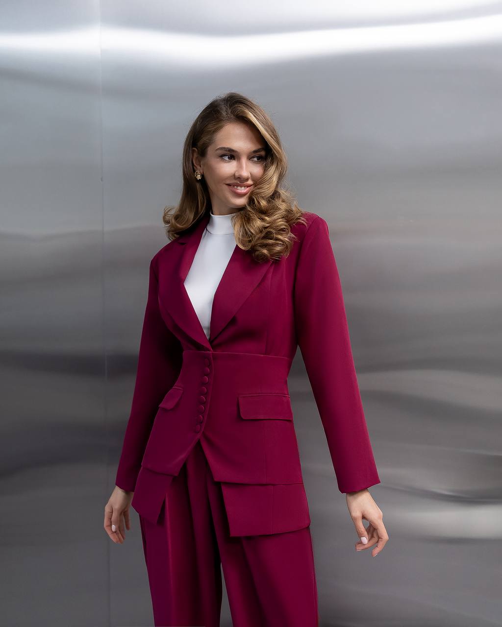 Woman wearing a magenta suit against a metallic background