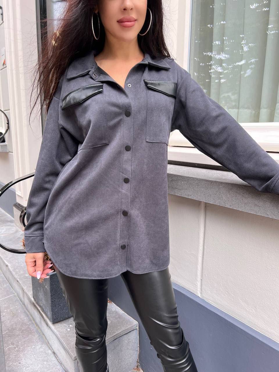 Person wearing a gray button-up shirt and black leather pants standing outdoors.