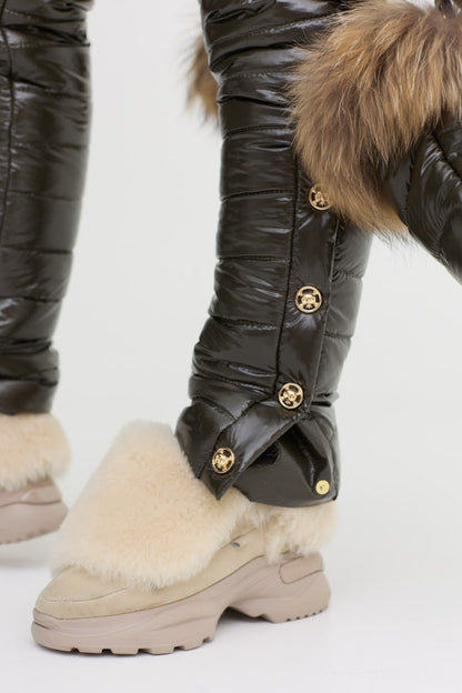 Close-up of beige winter boots with fur lining and black quilted leg warmers on a white background