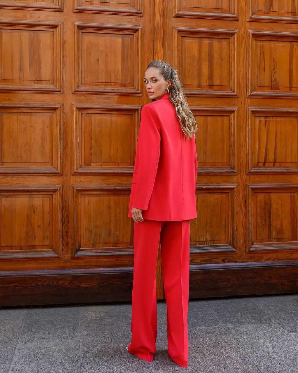 Person wearing a red suit standing in front of a wooden door.