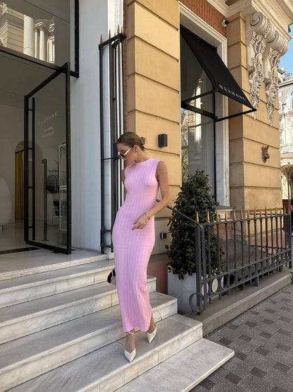 Woman in a pink dress walking out of a building with decorative architecture.