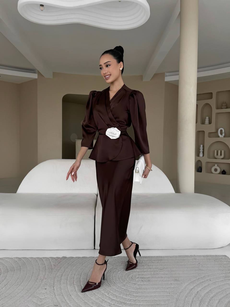 Woman in a brown outfit standing in a modern interior setting
