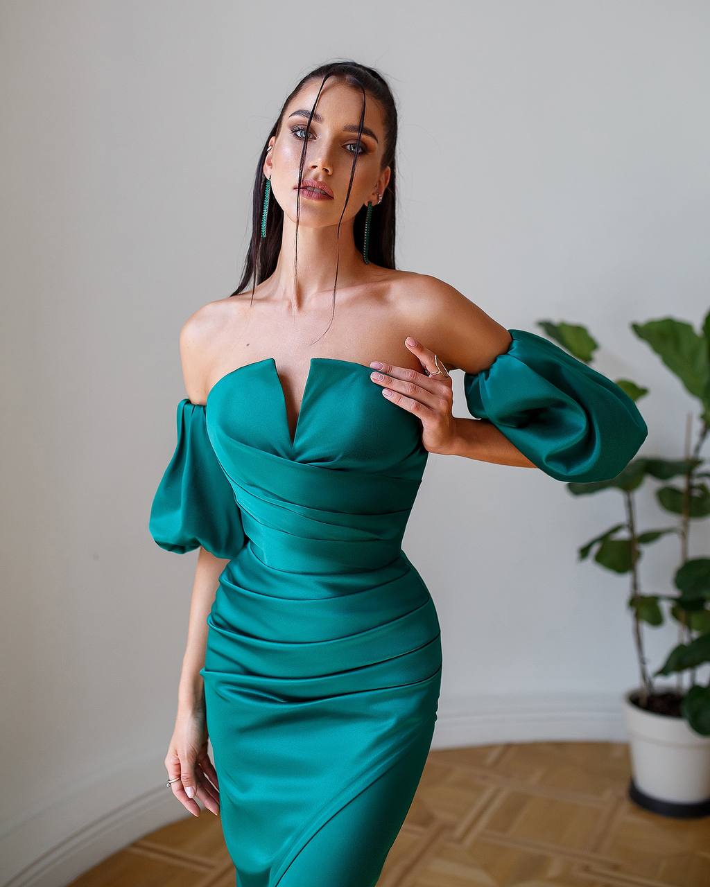 Woman wearing a green dress with puffed sleeves in an indoor setting.