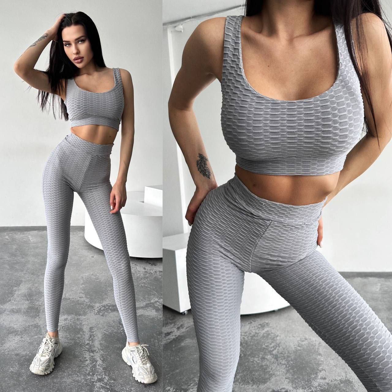 Woman wearing a gray athletic outfit in a minimalistic indoor setting