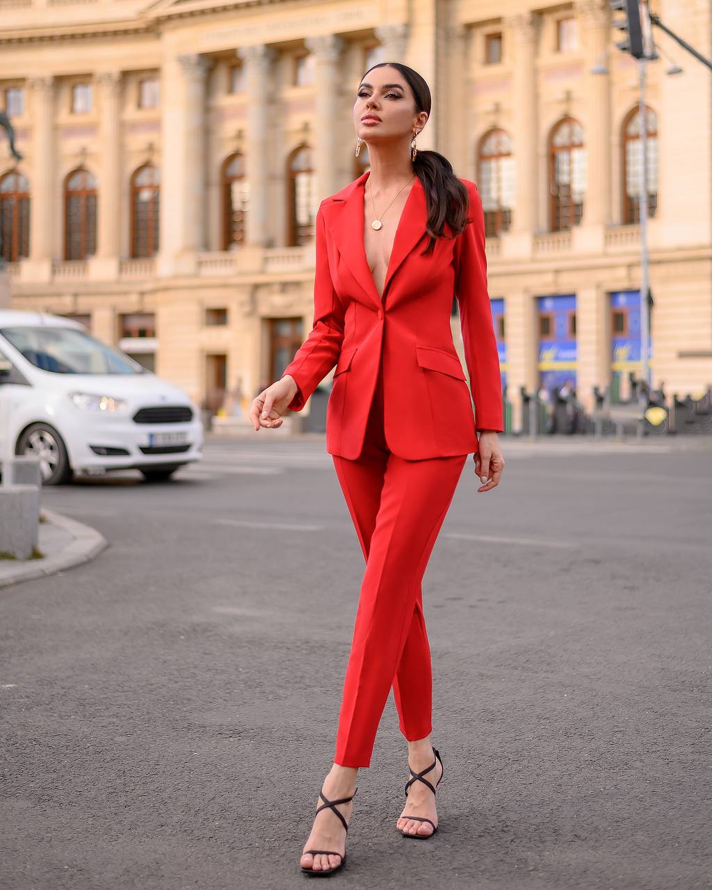 Woman in a red suit standing on a street with a building in the background