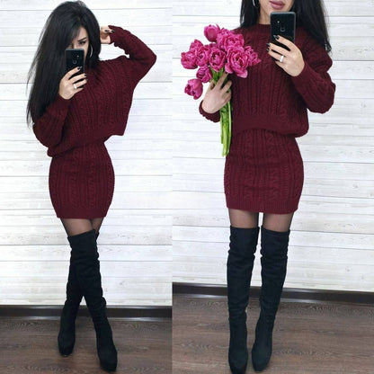 Woman wearing a burgundy cable knit dress with black knee-high boots, holding pink flowers.