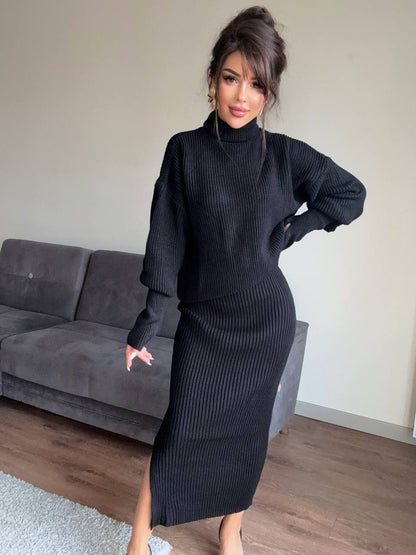 Woman wearing a black ribbed knit dress standing in a room with a gray couch.