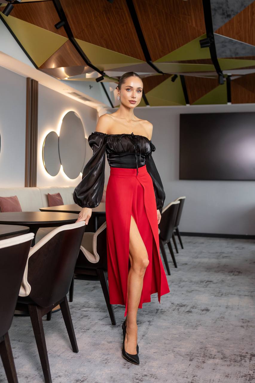 Woman in a black top and red skirt standing in a modern restaurant setting