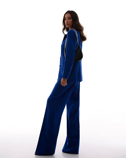 Woman wearing a blue outfit with a black bag on a white background