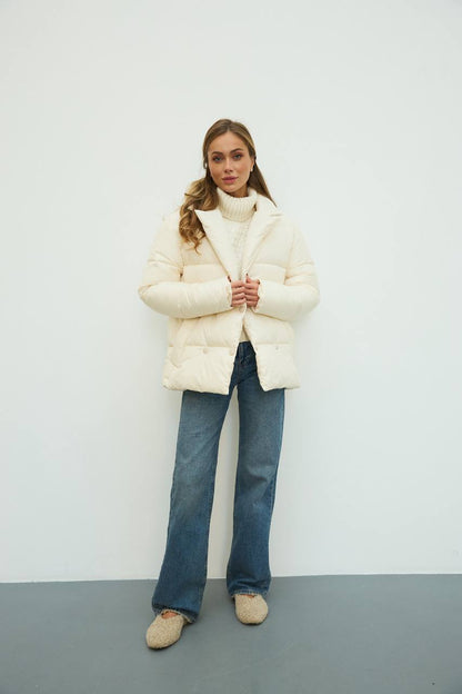 Person wearing a white puffer jacket and blue jeans against a plain background