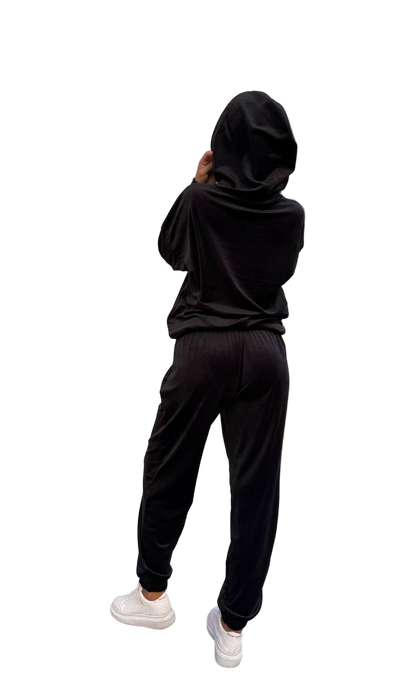 Person wearing a black hoodie and pants on a white background