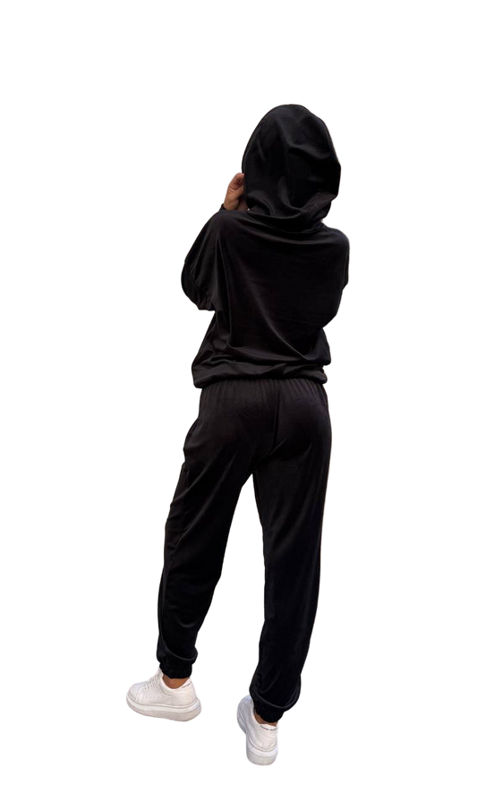 Person wearing a black hoodie and pants on a white background