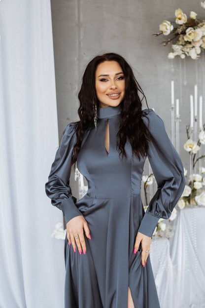 Woman in a gray dress standing in a decorated room with flowers and candles.