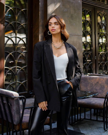 Woman in a stylish outfit standing outdoors near decorative metalwork.