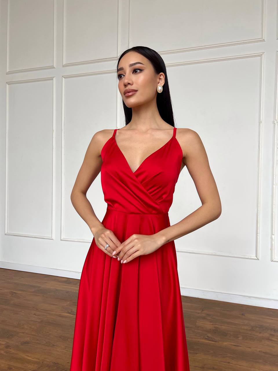 Woman wearing a red dress against a white paneled wall.