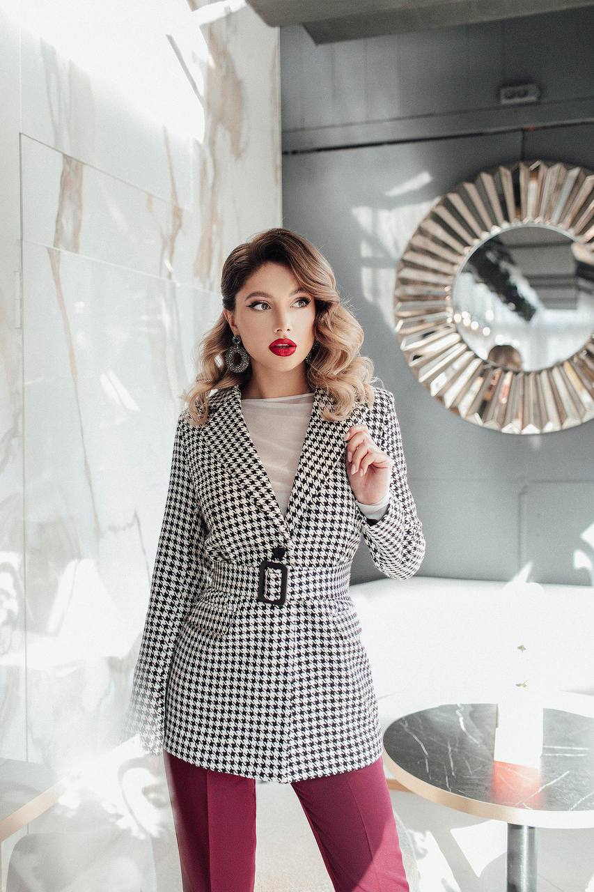 Woman wearing a black and white checkered blazer in an indoor setting.