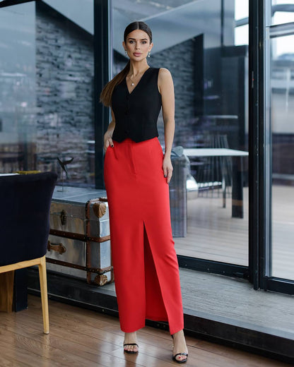 Woman in black top and red pants standing in a modern interior setting.