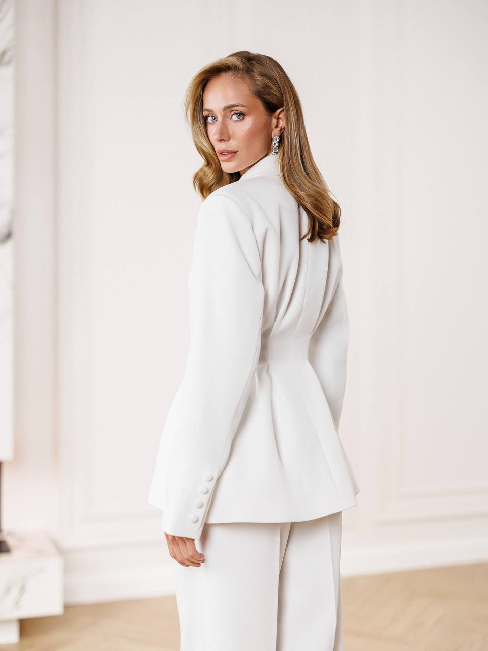 Woman wearing a white suit against a neutral background
