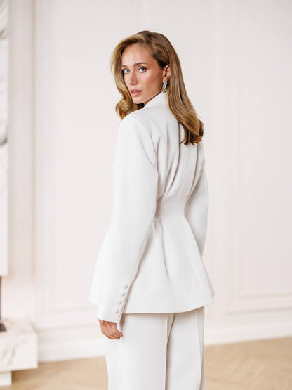 Woman wearing a white suit against a neutral background