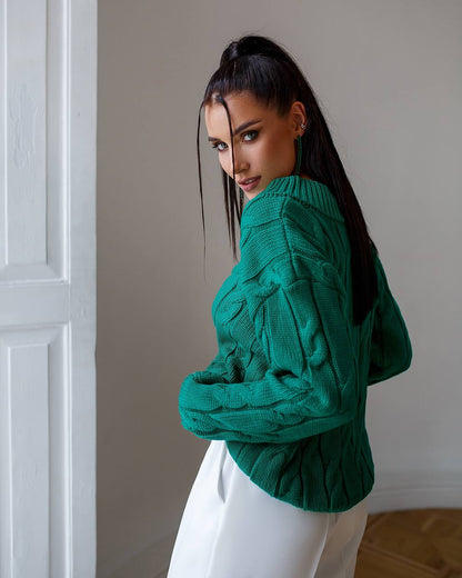 Woman wearing a green sweater against a neutral wall
