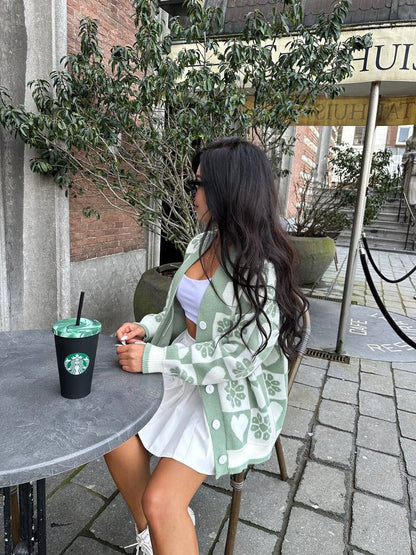 Woman sitting outdoors with a Starbucks cup, wearing a green patterned cardigan.