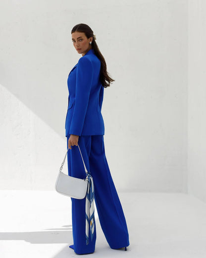 Woman in a blue suit holding a white handbag against a white background