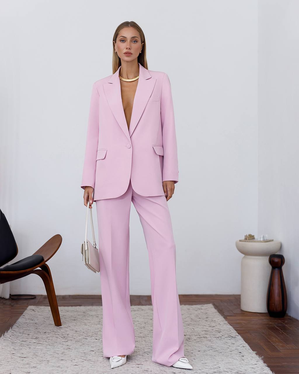 Woman wearing a pink suit in a minimalistic room.