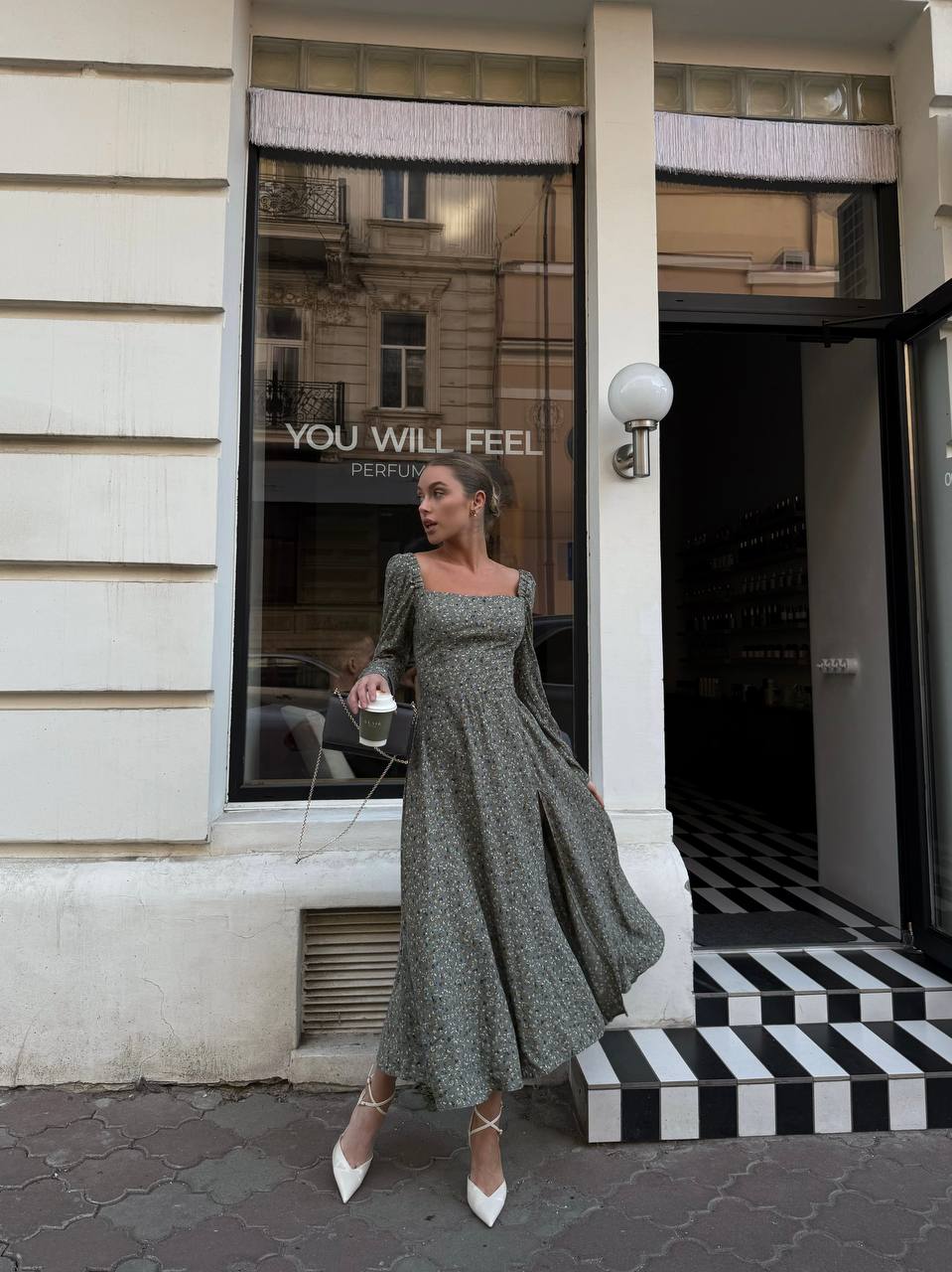 Woman in a green dress standing outside a building with a store front.
