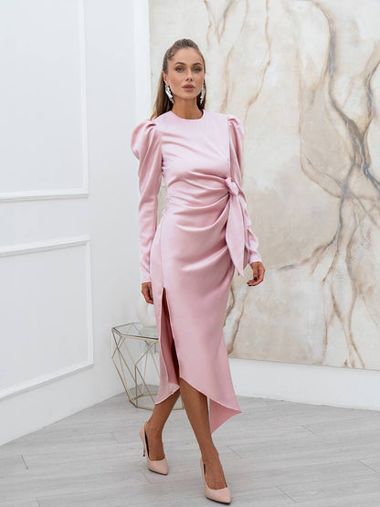 Woman wearing a pink dress with long sleeves and a marble wall background