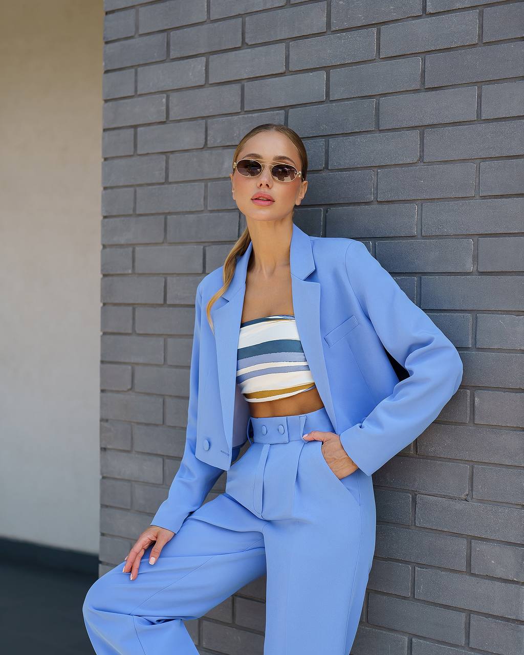Woman in a blue suit standing against a gray brick wall