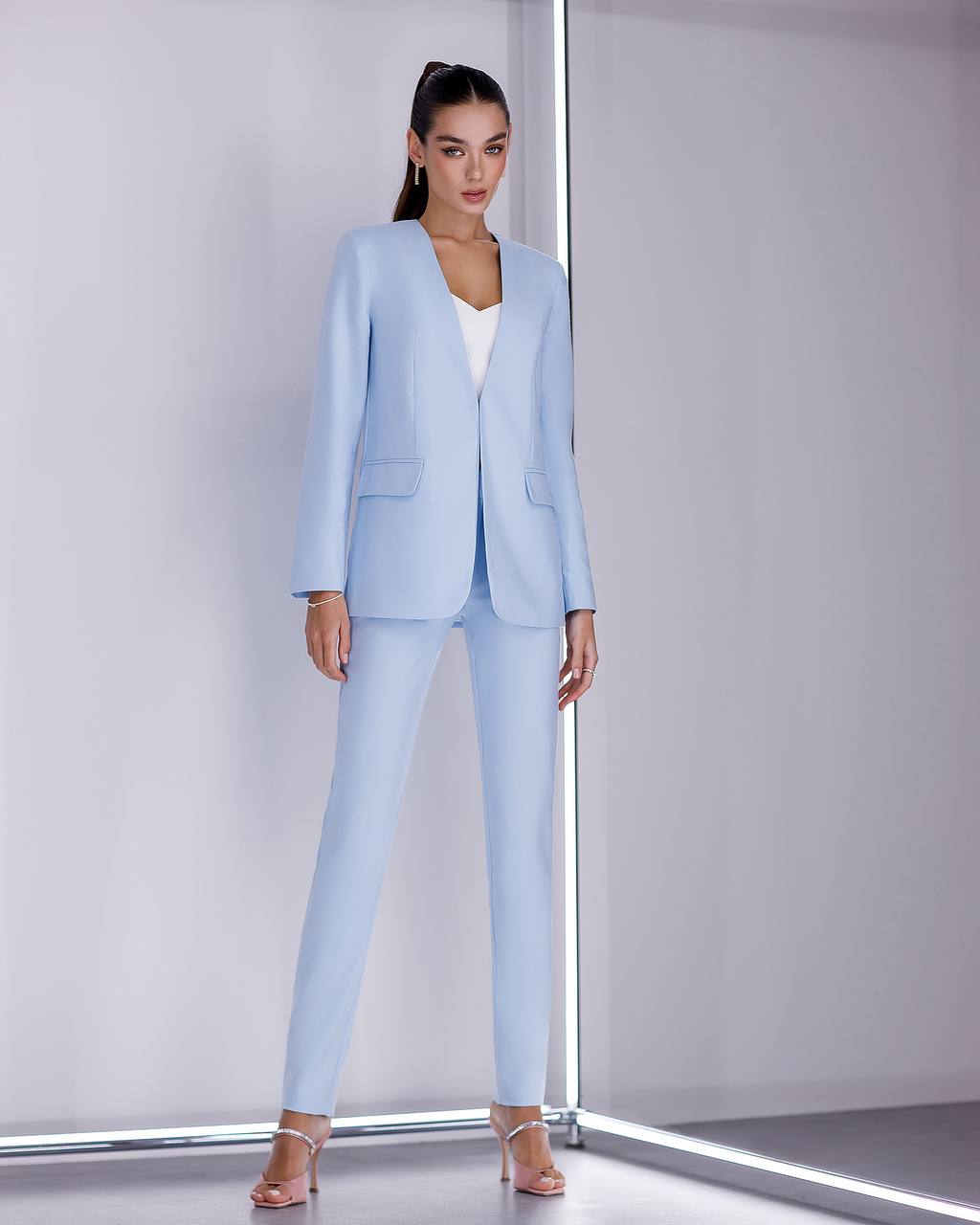 Woman wearing a light blue suit standing against a white background